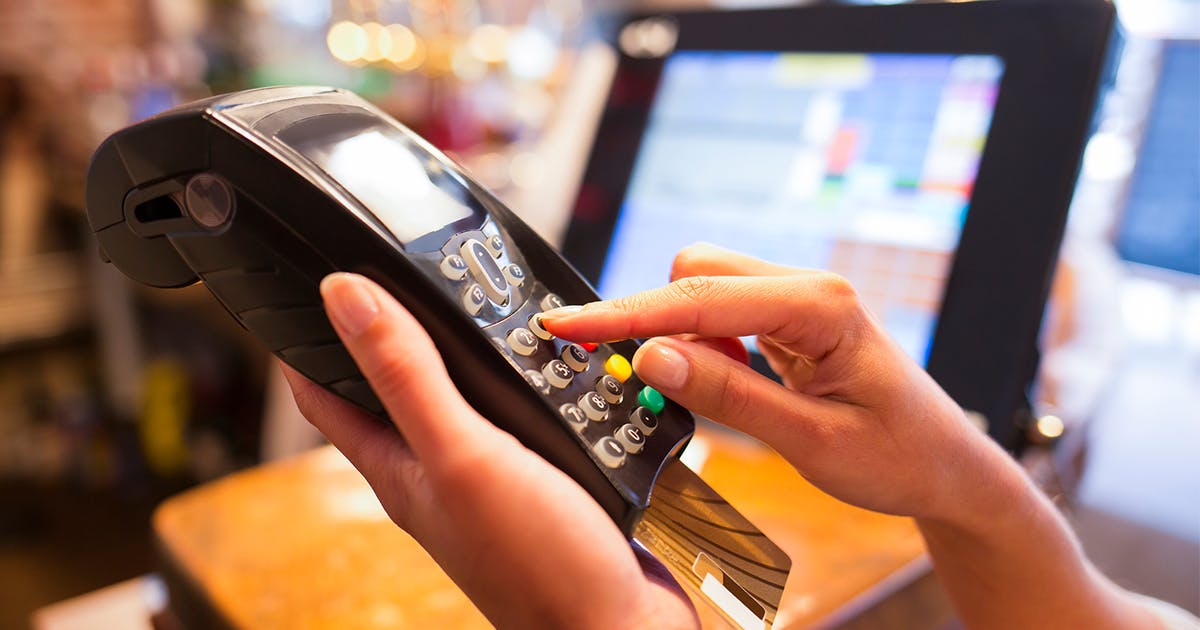 mão segura e aperta botão na máquina de cartão de crédito