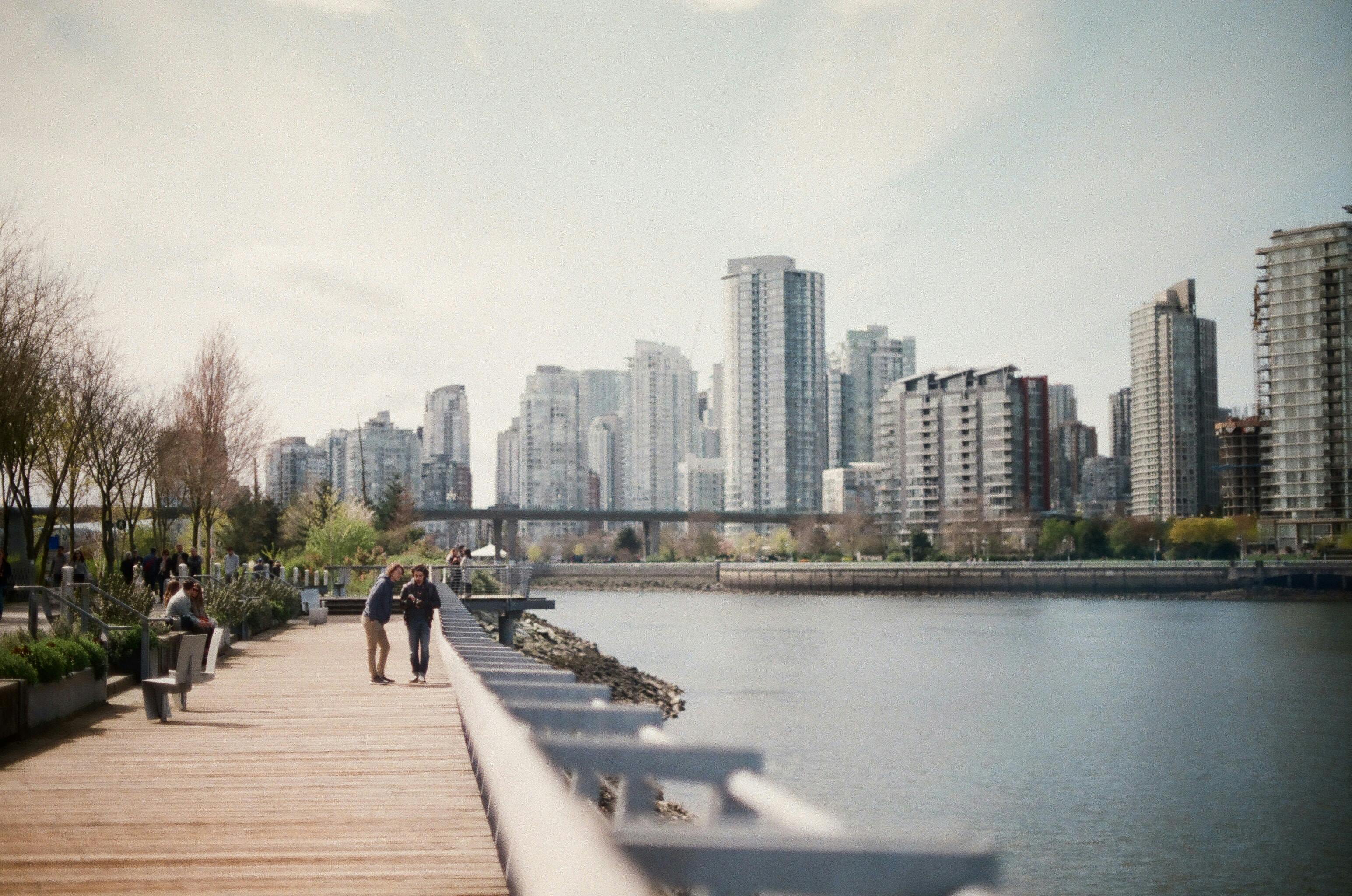 Visão de uma ponte e um lago com a cidade de Vancouver ao fundo.