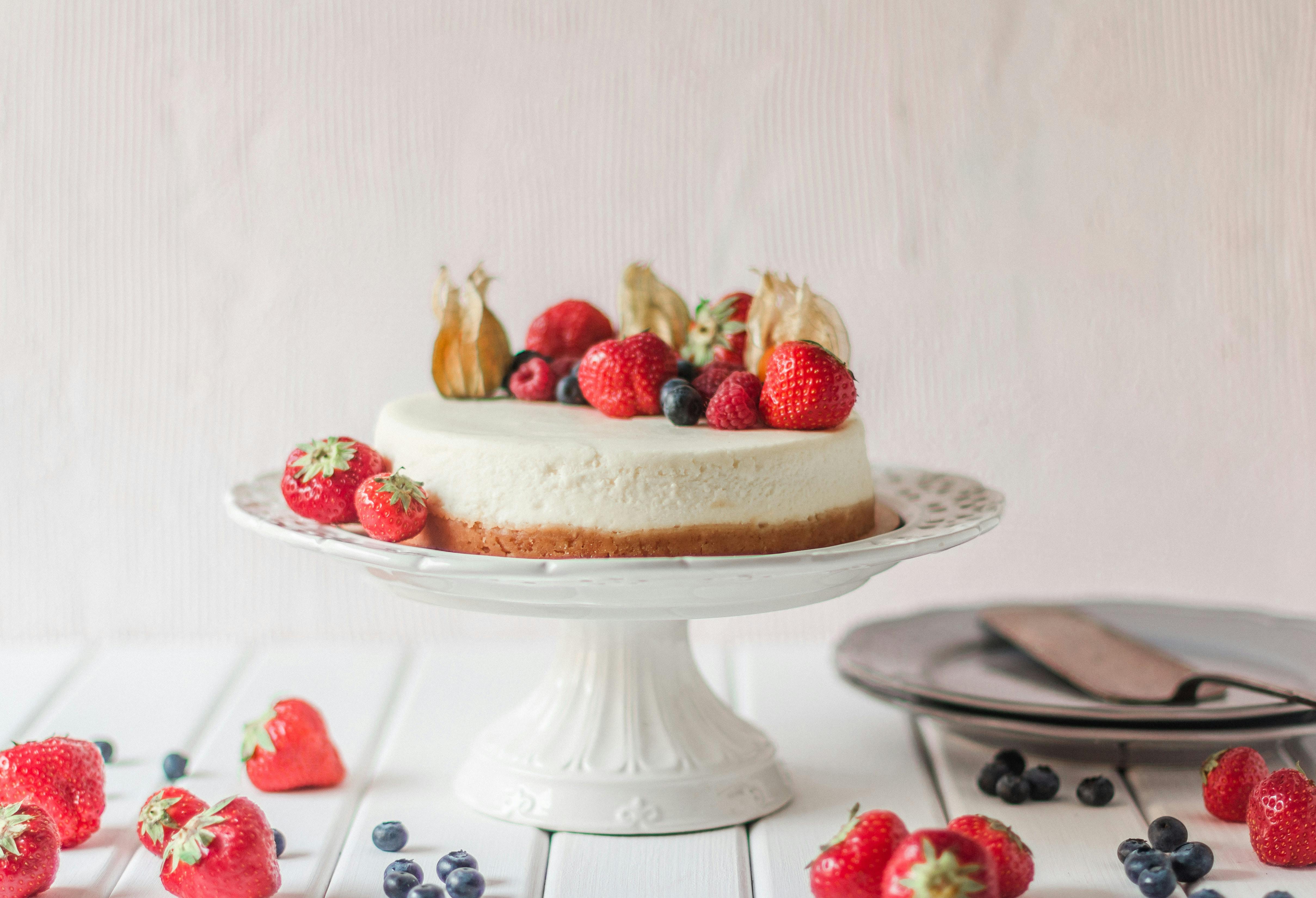 Victoria's sponge cake, uma das comidas típicas da Inglaterra, apresentada em um prato branco decorativo e frutas vermelhas.