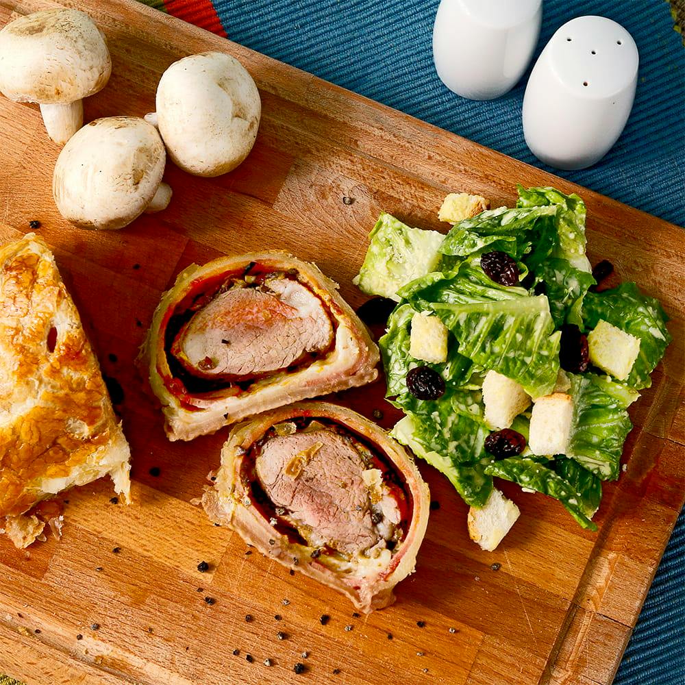 Beef Wellington, um prato típico inglês, visto de cima em uma tábua de madeira.
